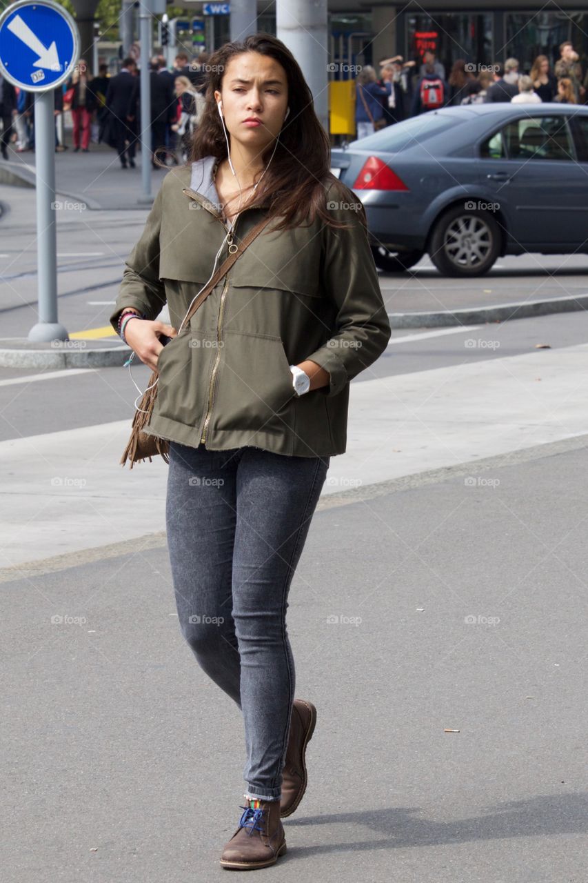 Girl With Earbuds Walking On Sidewalk