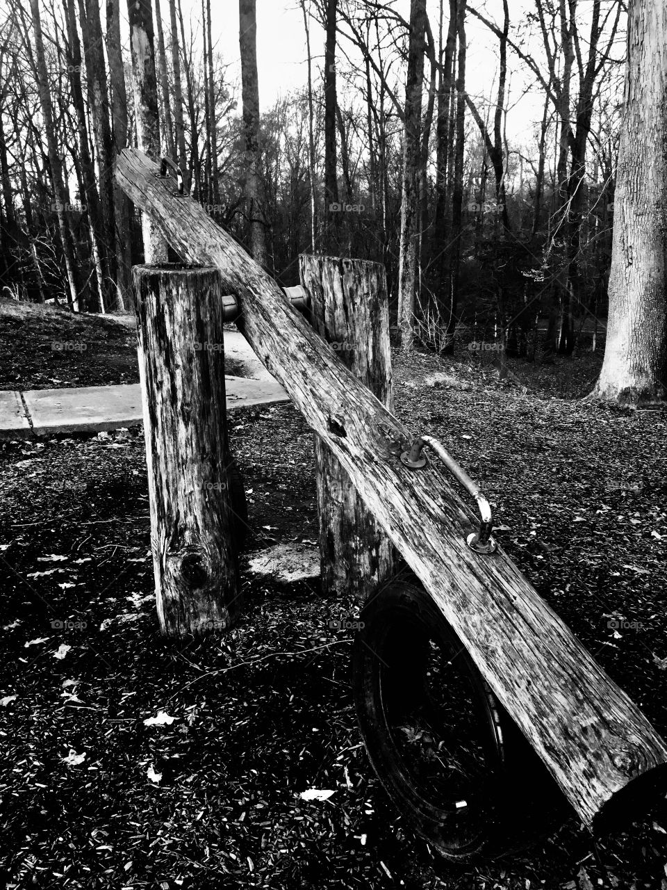 Black and white of a rustic wooden log seesaw at the playground at White Deer Park in Garner, North Carolina, Raleigh Triangle area. 