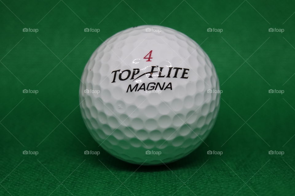 Topflite magna 4 white golf ball on dark green background.
