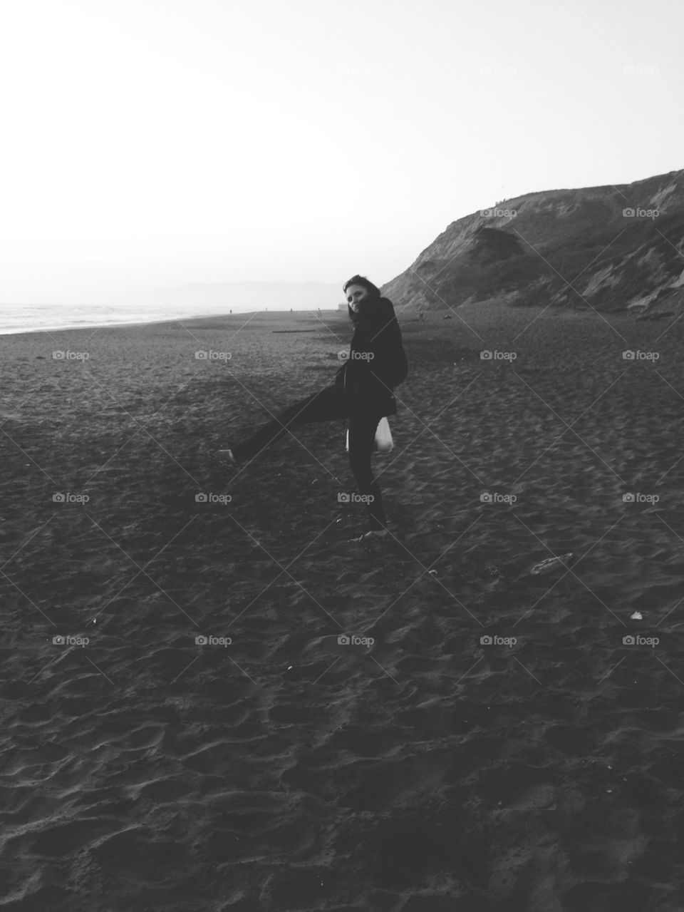 WOMAN PLAYING ON GREY BEACH