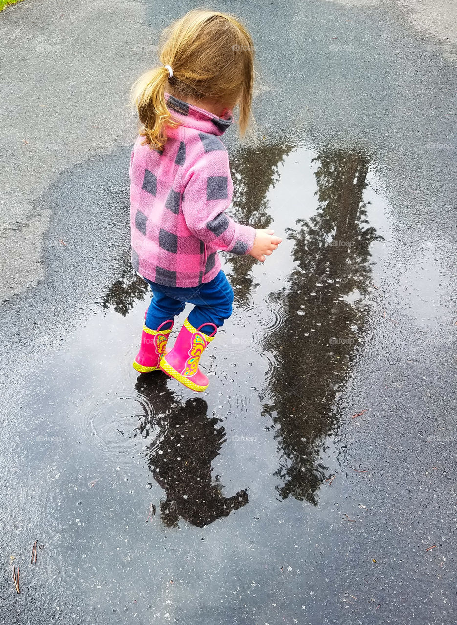 Little girl splashing in a puddle while camping.