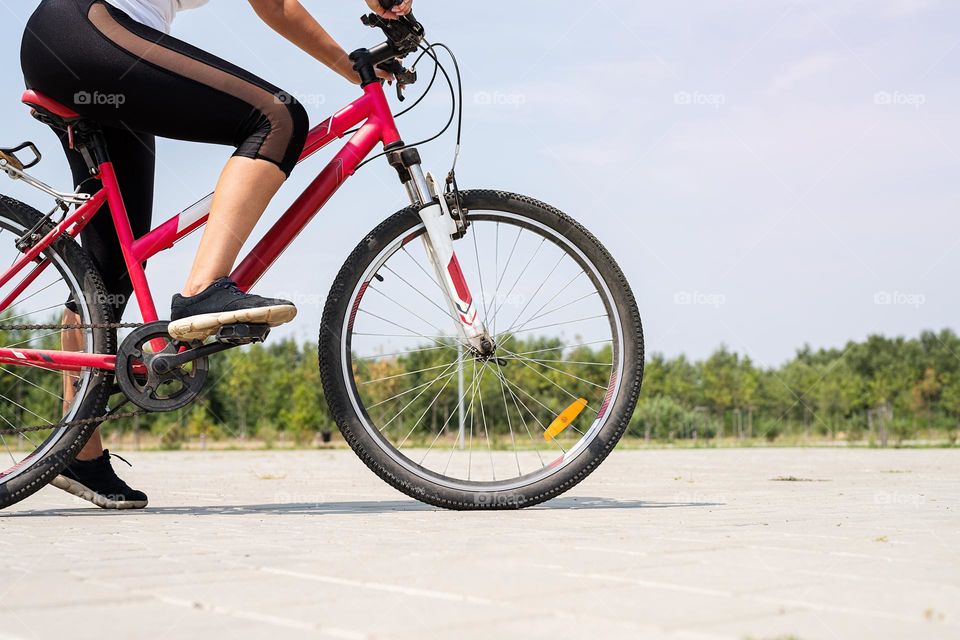 woman in sports clothes and cap riding her bicycle