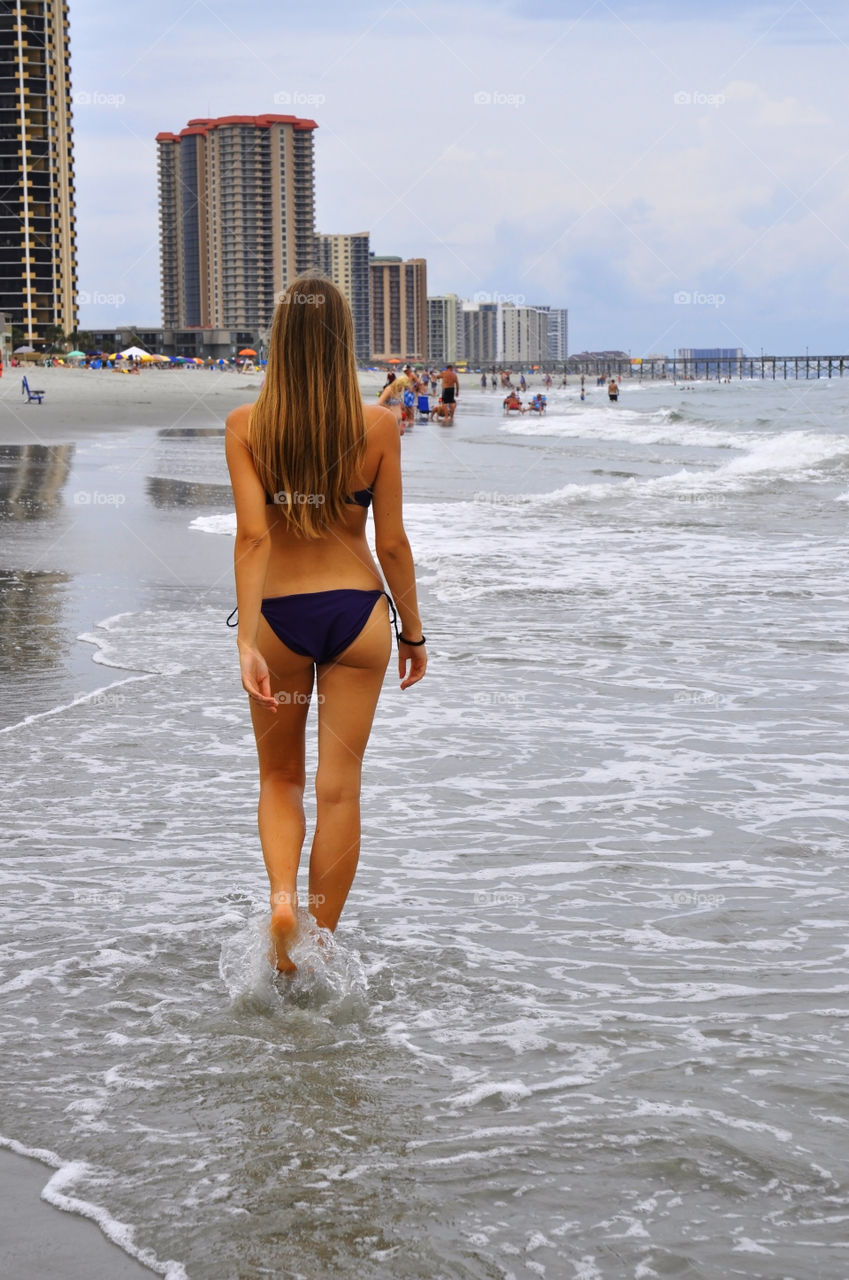 A. Beautiful young woman walks down the beach.