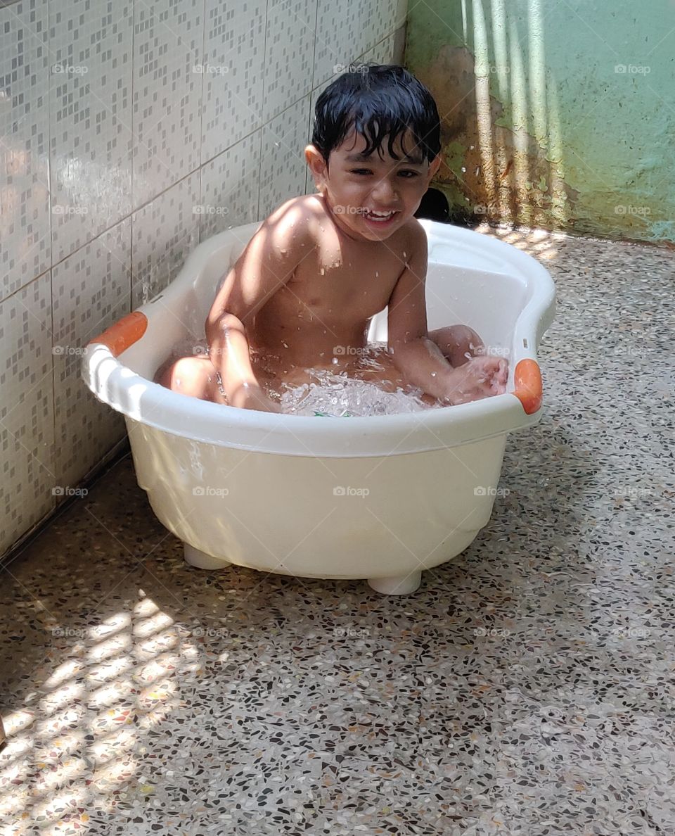 happy kid enjoying his bath in tub in summer