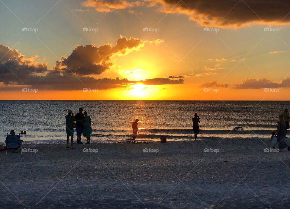 Family and friends watching the oceanside sunset on Manasoto Key, Florida.