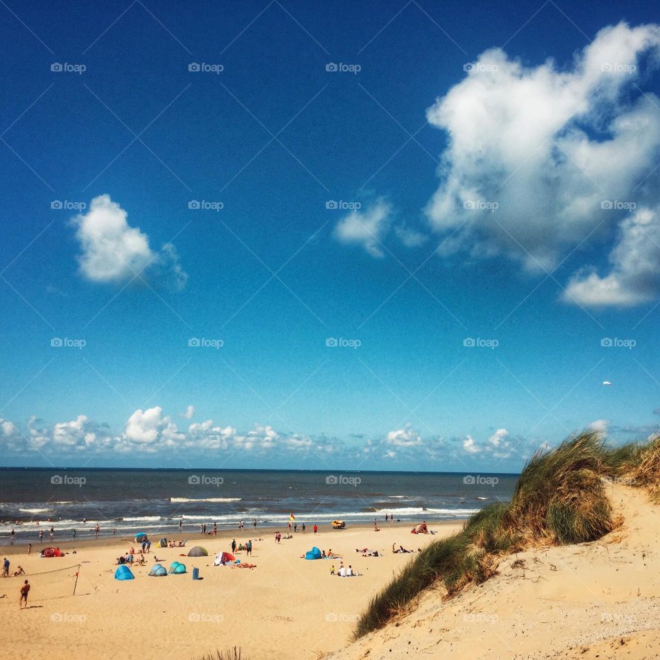 Lovely summer day at the sea. Beach and sea and dunes, people on the beach, enjoying the sunny day
