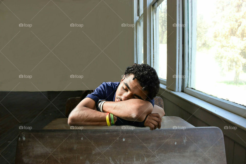 Young Student Sleeping On Desk In Classroom