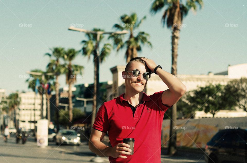 Young happy handsome bearded man, tourist in sunglasses. Guy walking in old city of Koper,  Slovenia