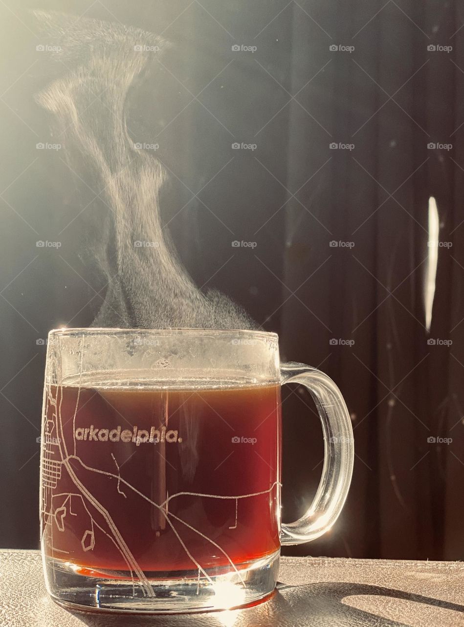 Coffee steam rises from a glass mug