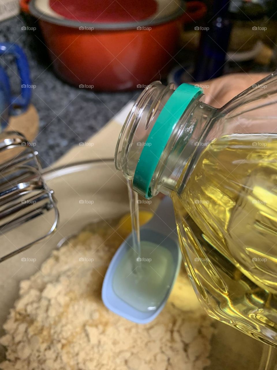 Liquids are cool - A stream of vegetable oil is captured in a blue measuring spoon prior to pouring it into the dry ingredients 