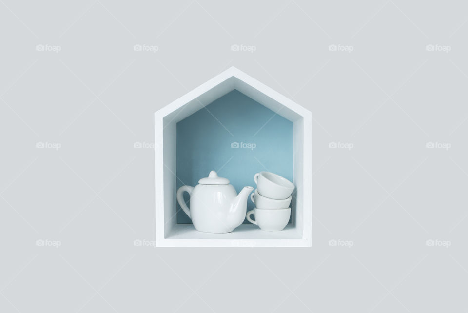 Teapot and cups in little wooden house 