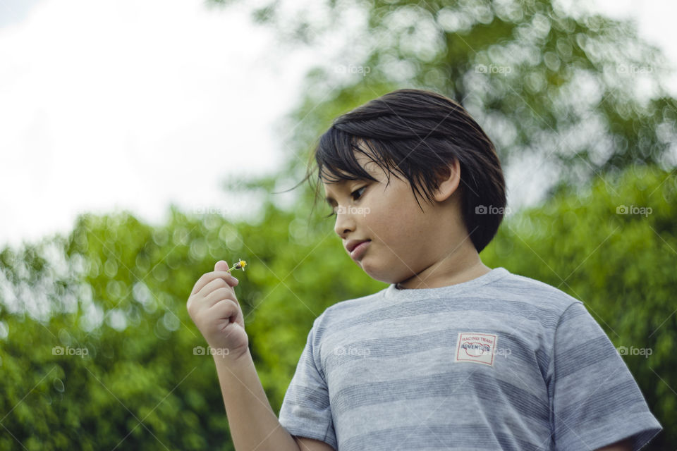 outdoor portrait of happy young eurasian boy on a blurry out of focus bokeh foliage background