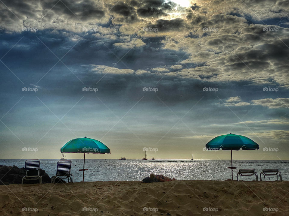 Social distancing on the beach, two bright green beach umbrellas placed far apart