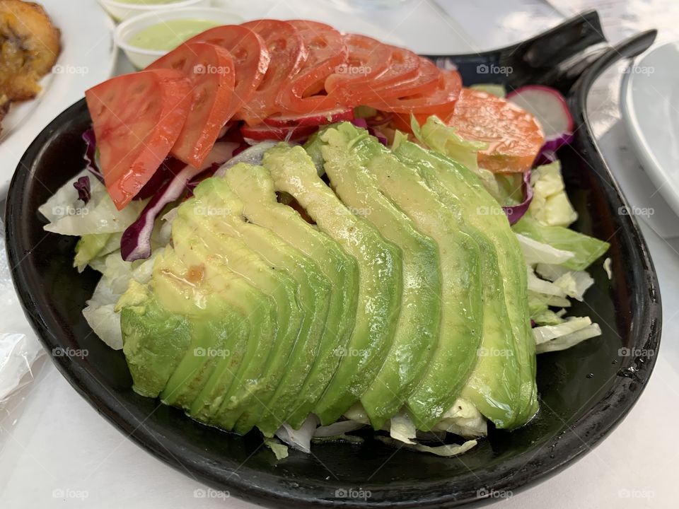 Healthy avocado salad with tomatoes, lettuce, and red radish for lunch or dinner.