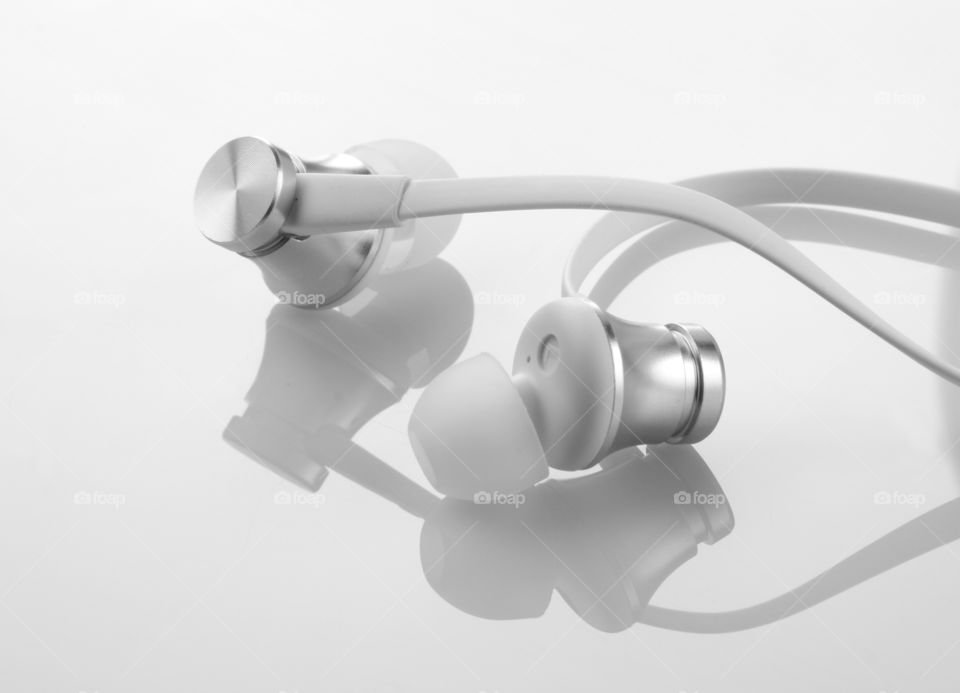 Wires earphones / headphones on white reflective background