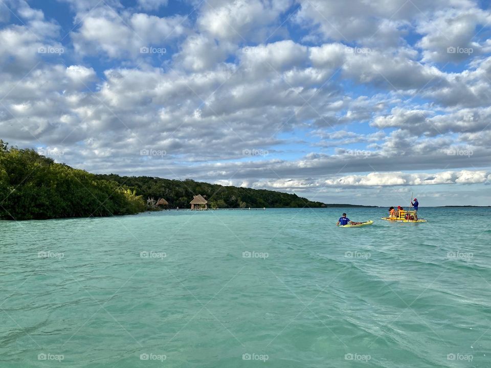A lovely lagoon with a raft and a person with a paddleboard in the distance