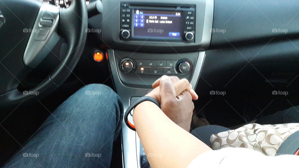 Couple holding hands while driving.