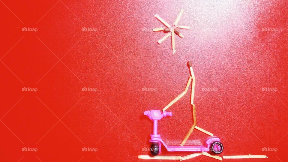 wooden match person riding a pink scooter