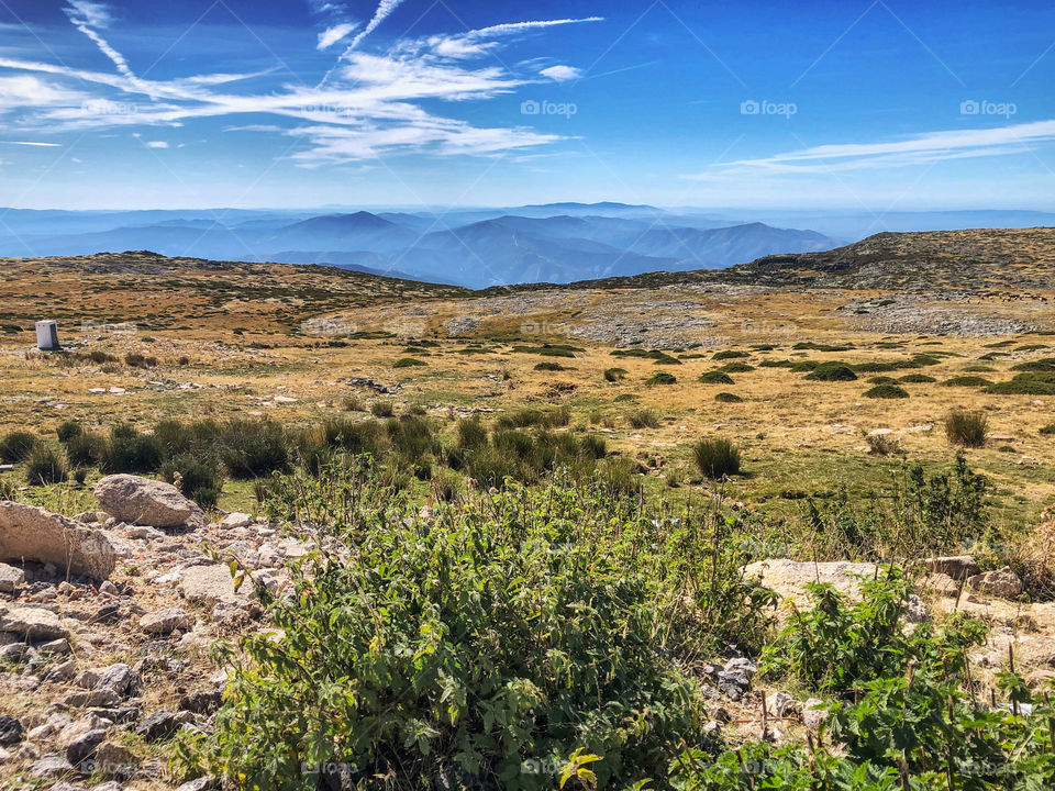 A landscape view at Serra Da Estrela national park, cloud can be see swirling around the mountains in the distance, on an otherwise sunny day