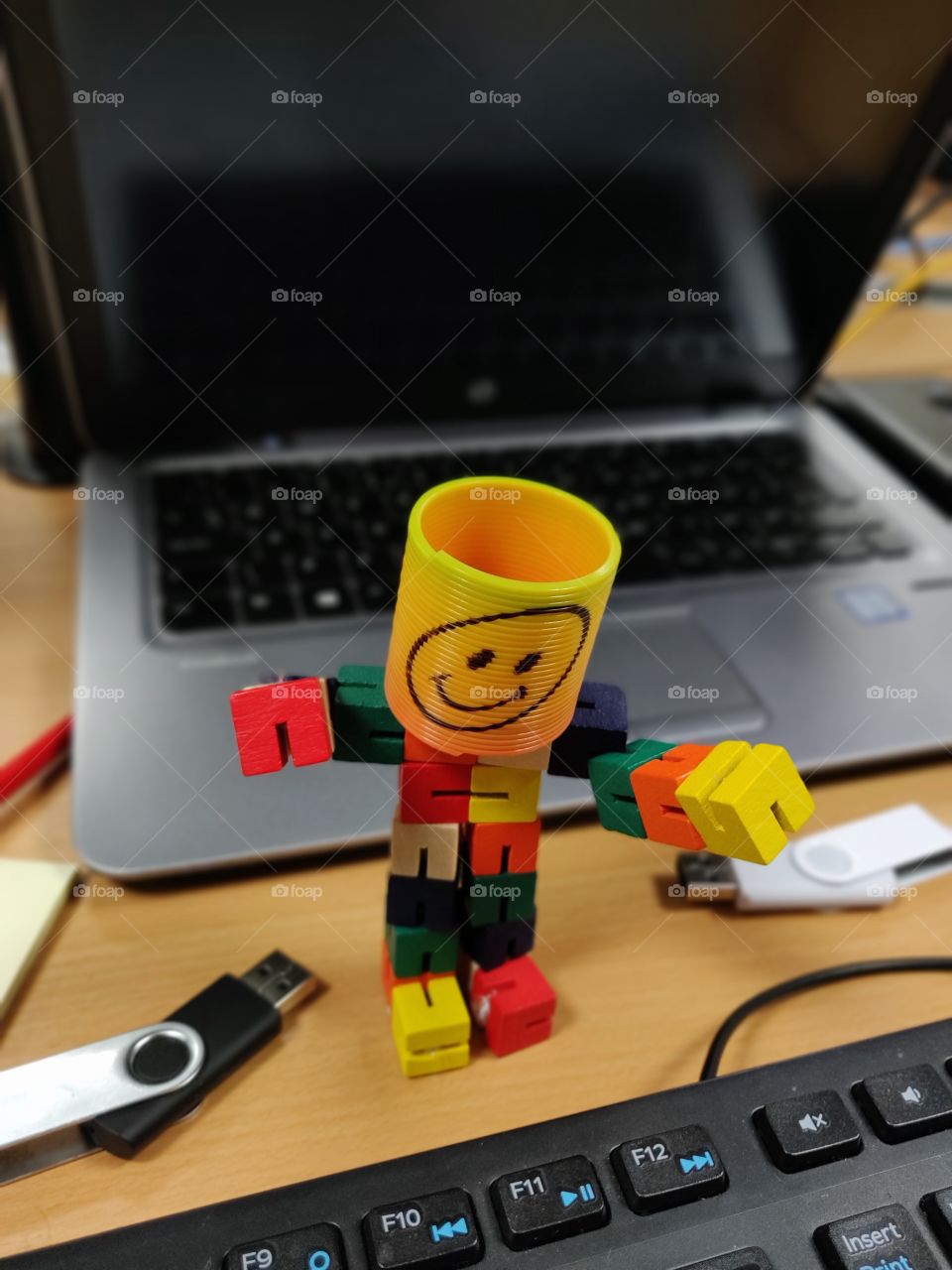Smiley emoji man on the office desk by the laptop and keyboard