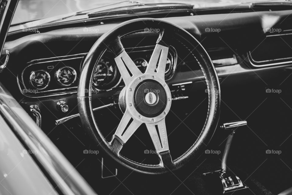 A portrait of a dashboard, steering Wheel and shift stick of an classic oldtimer car.