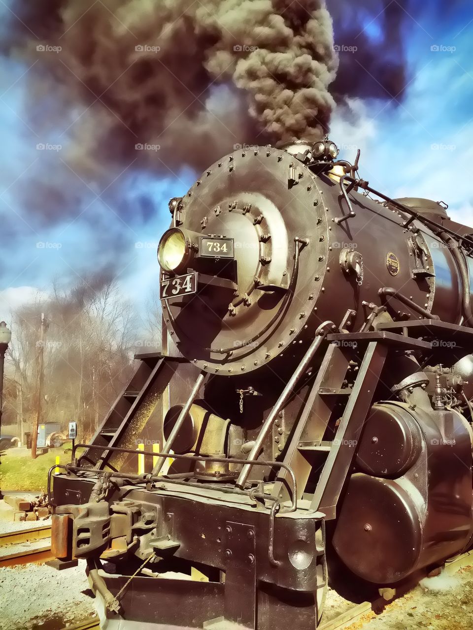 A steam engine pulling a train on the railroad tracks. 