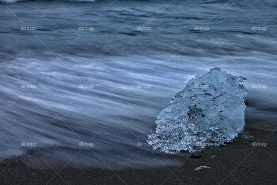 Glacial ice on black beach in the breaking waves
