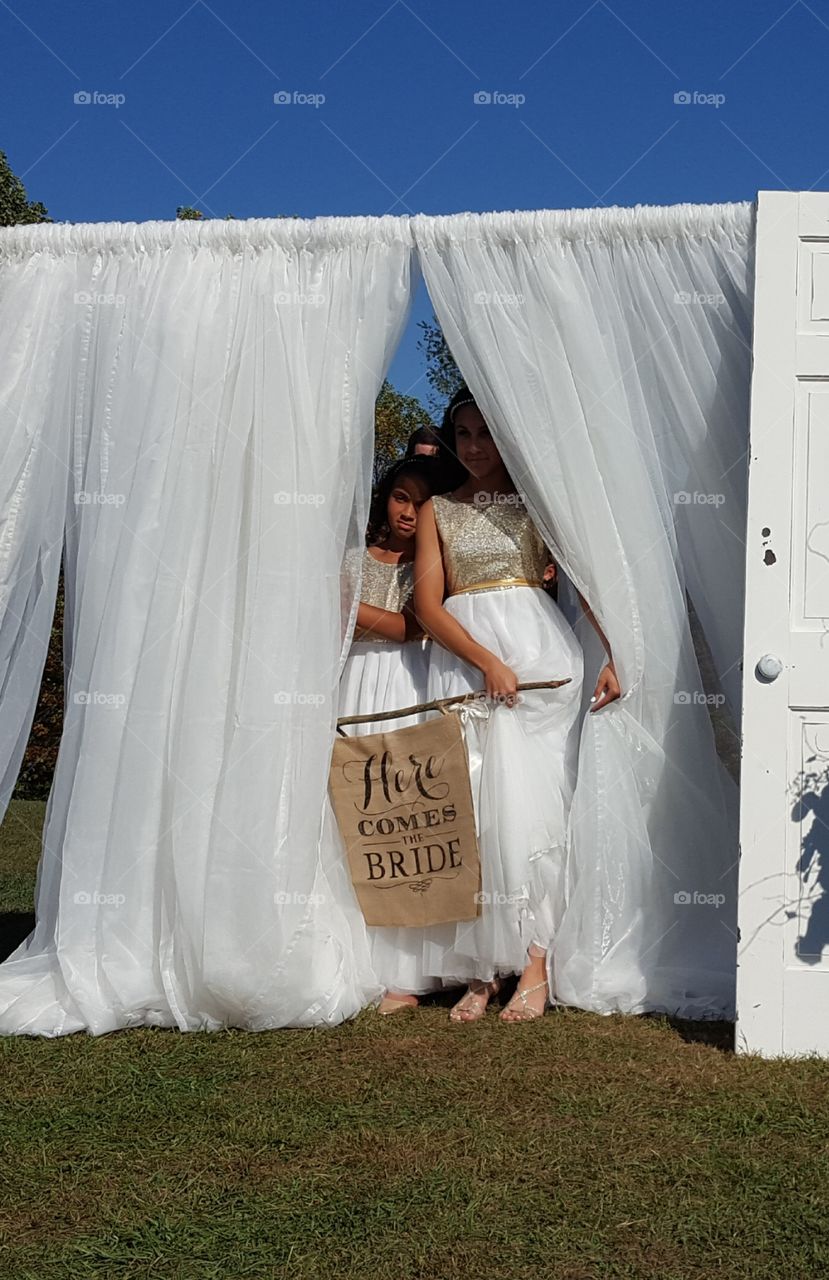 Flower girls peek out from behind the curtains ready to announce 'here comes the bride!'.