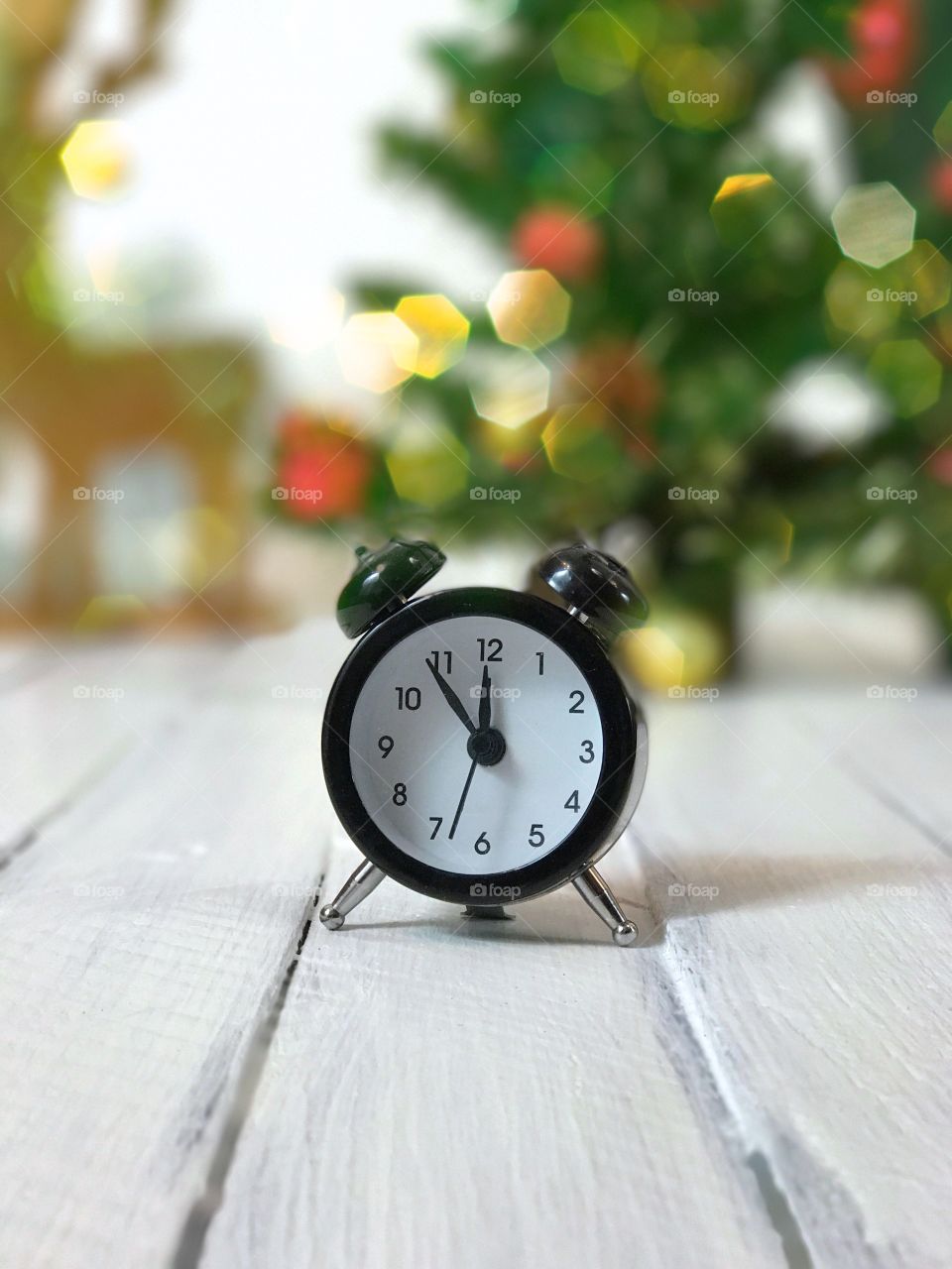 Vintage clock is five minutes to midnight, blur the background with a Christmas tree