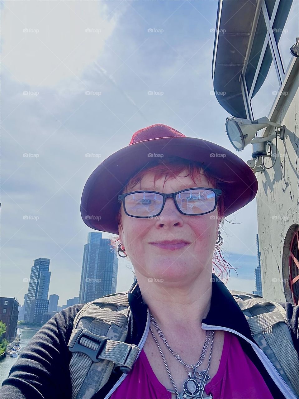 This is me, “Petra Schiller” a.k.a. “Maxine Firefox” standing by the center outpost of the “Pulaski Bridge” at “Newtown Creek” that connects “Greenpoint”, Brooklyn to LIC, Queens on a bright sunny afternoon in May 2024. Hypnotic Productions