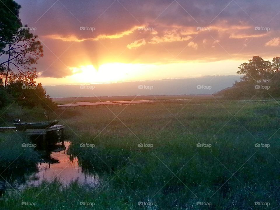 Beautiful sunrise over the marsh with a boat lifted onto a dock