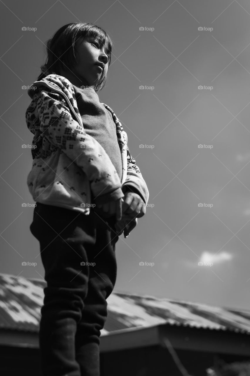 A black and white shot of a little girl looking at something in deep thought