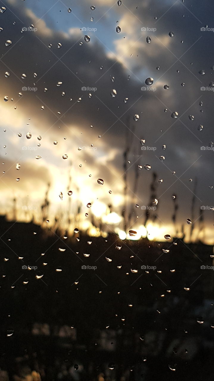 Raindrops on a window with sunset in the background