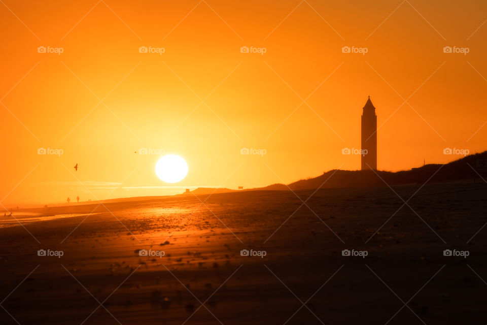 Golden seascape sunset as the sun nears the horizon next to a water tower