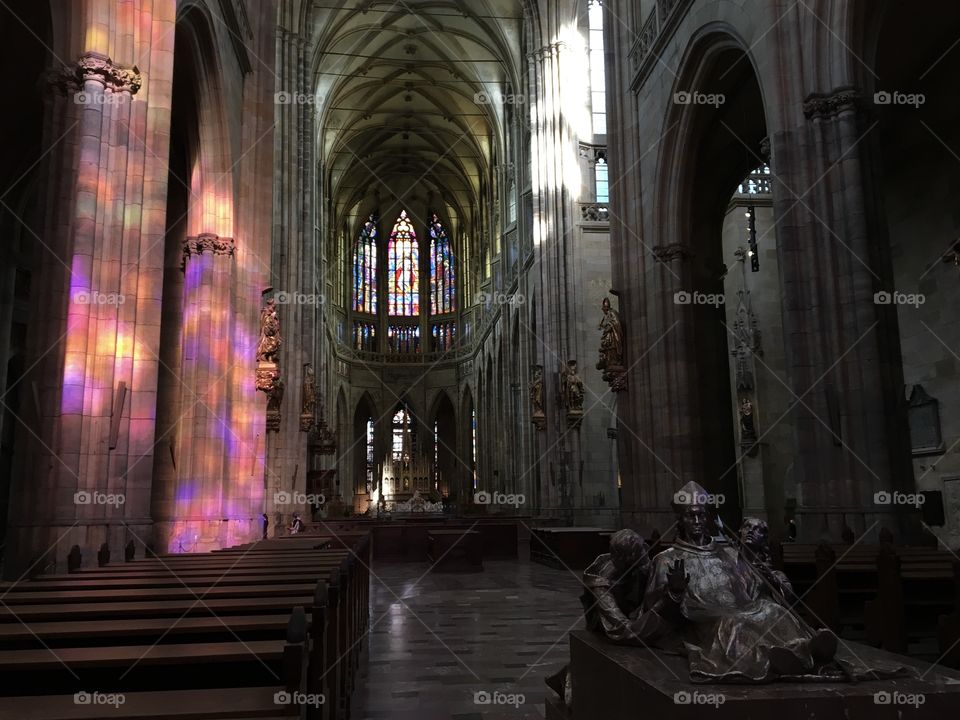 Colourful shades of purple and gold bouncing off a church pillar from the sunlight shining through the stained glass window 