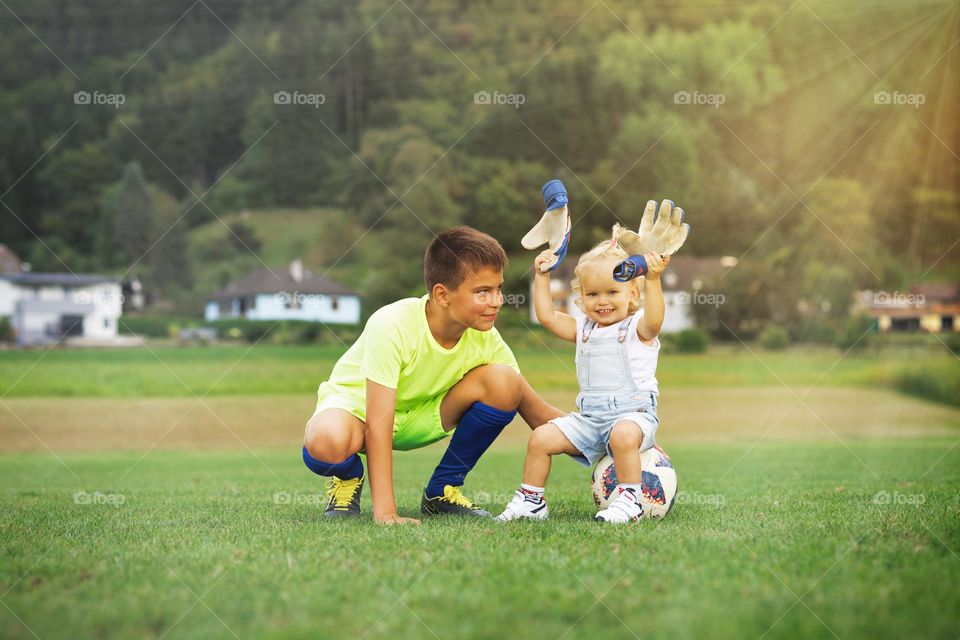 A little curly-haired girl and a teenager on the football field