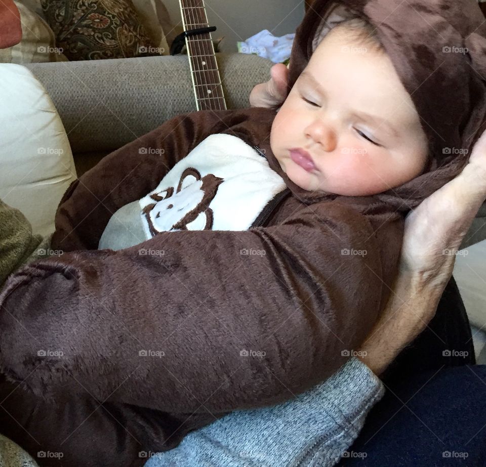 A sleeping baby boy with his little teddy bear outfit.
