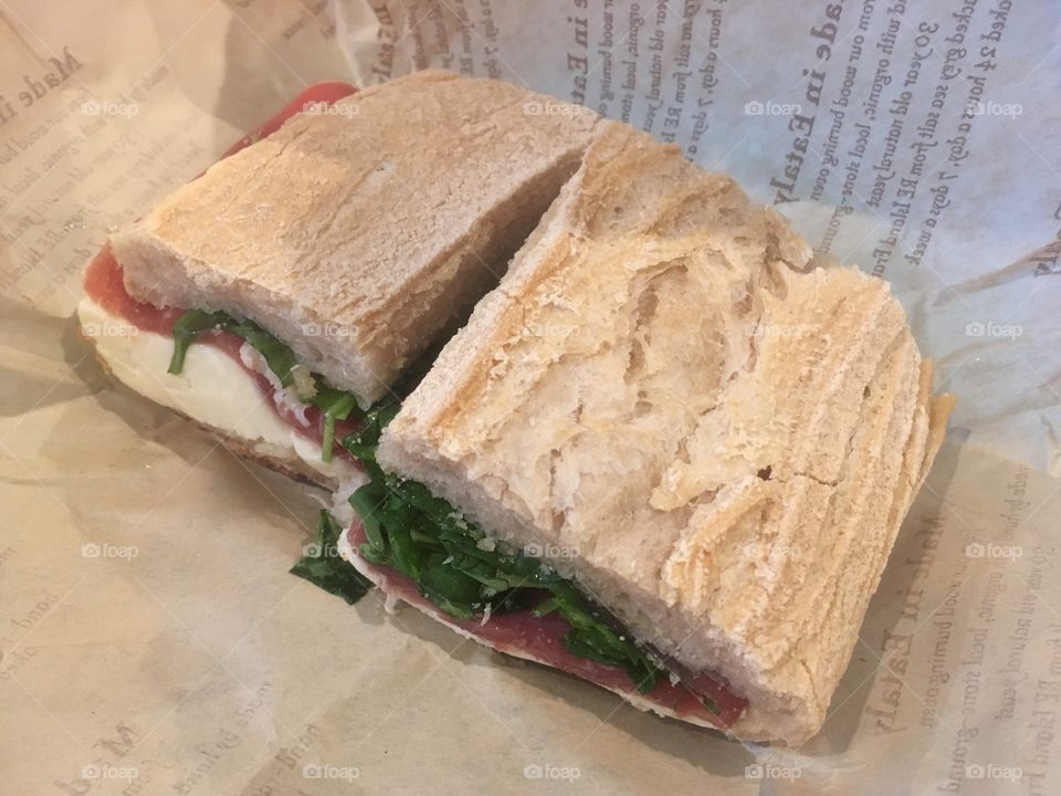 A sandwich from an Italian deli with white bread, prosciutto, mozzarella and tomato 