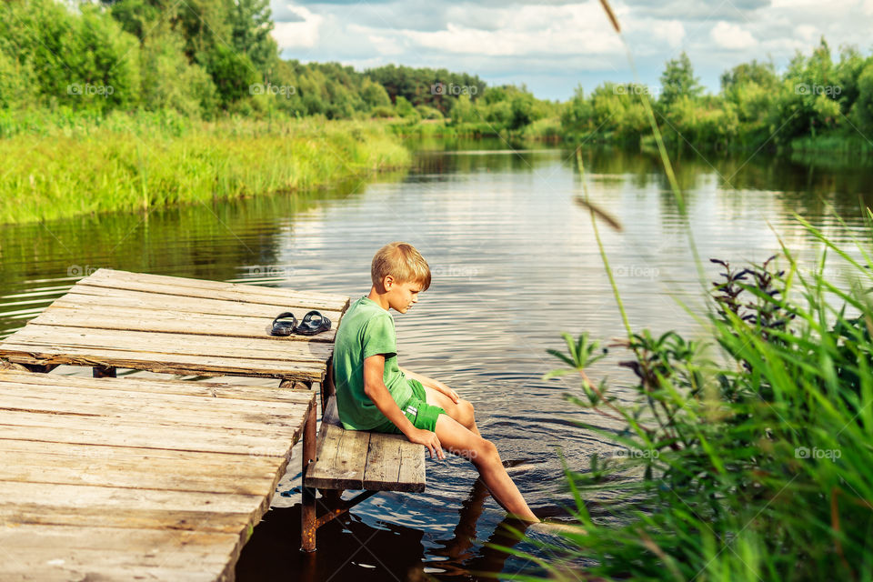 Boy is sitting near the peaceful lake