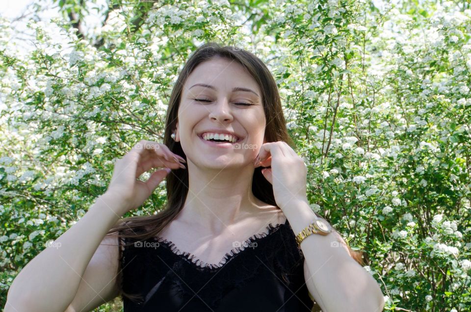 Smiling Young Girl on Background of Flowers