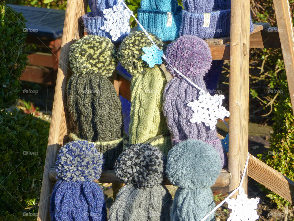 Hand knitted bobble hats. Hand knitted bobble hats displayed on a vintage wooden stepladder