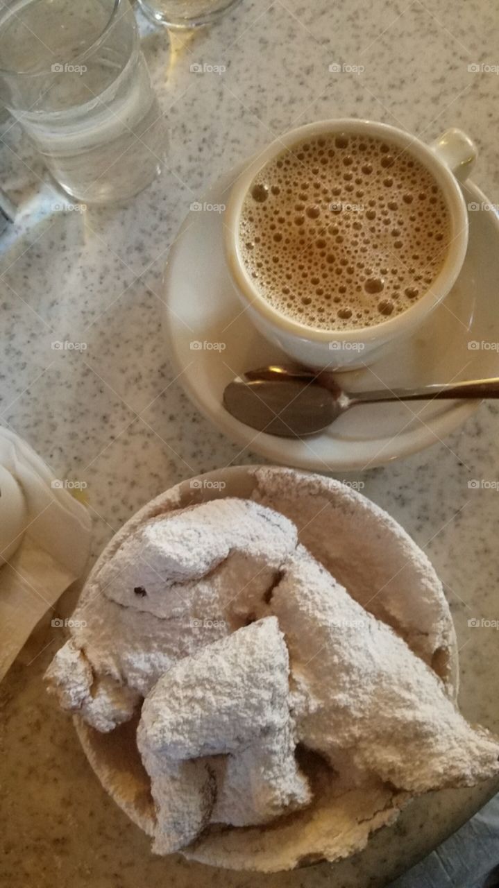 Cafe au lait with three freshly powdered beignets in New Orleans