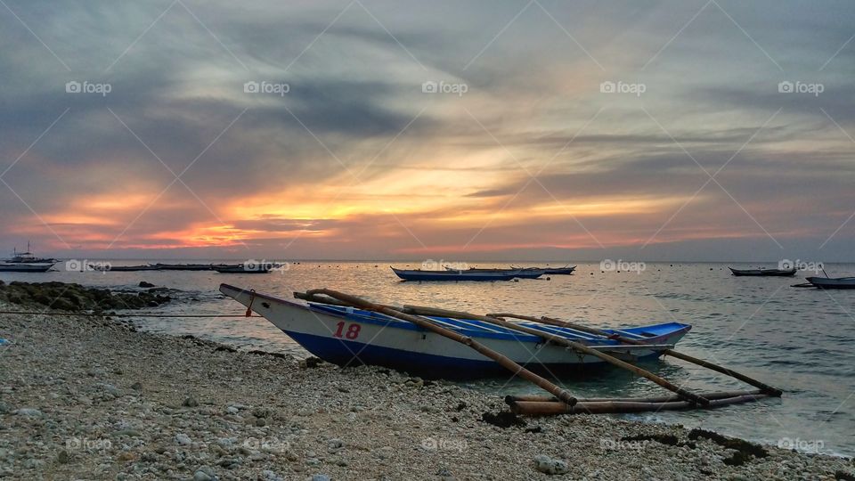boats by the shore during sunrise