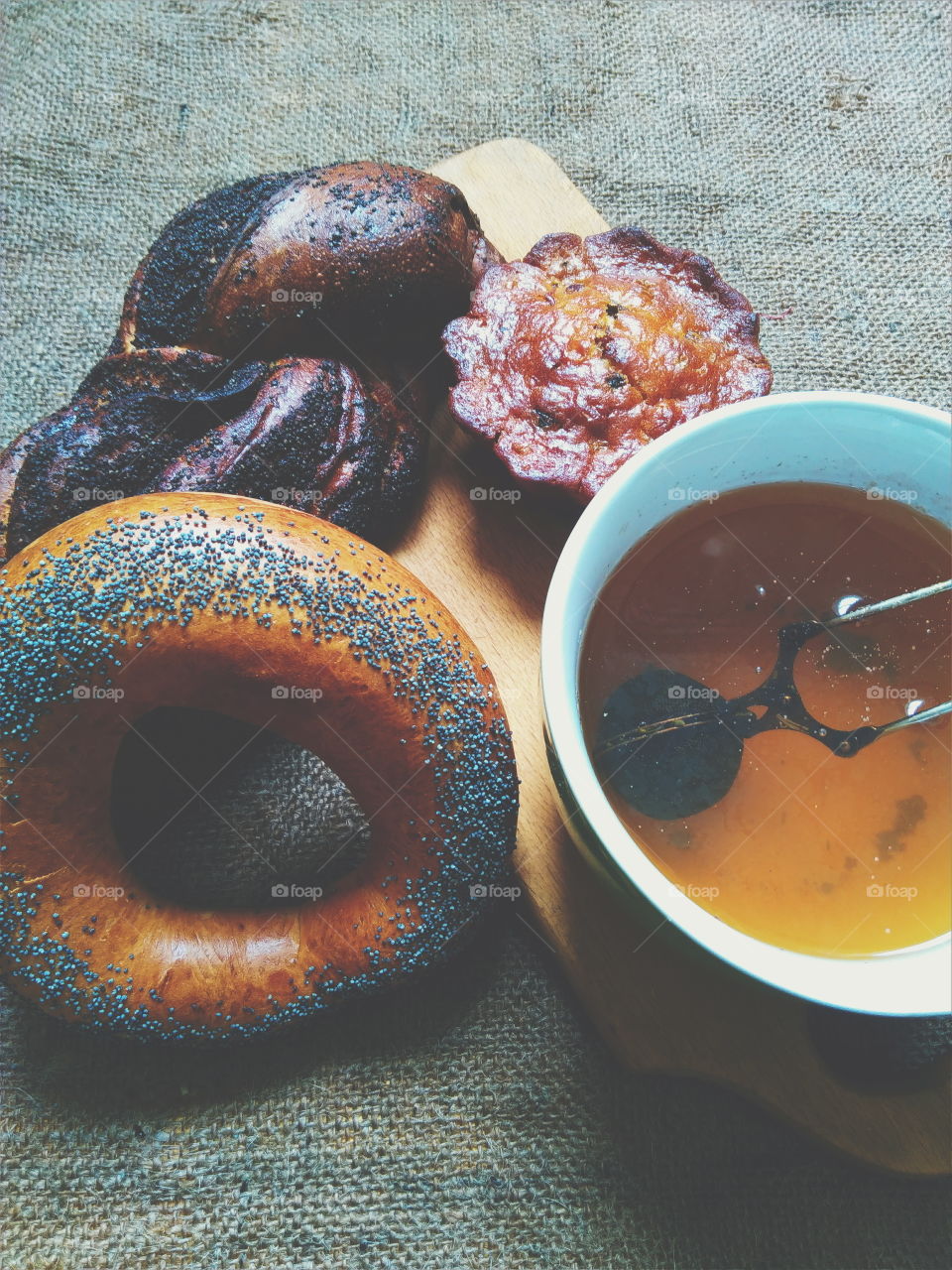 bagel with poppy seeds, basket with poppy seeds, vanilla cupcake and a cup of tea on the table