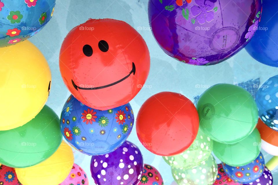 Bright Colorful balls with smiley face on one red ball in pool