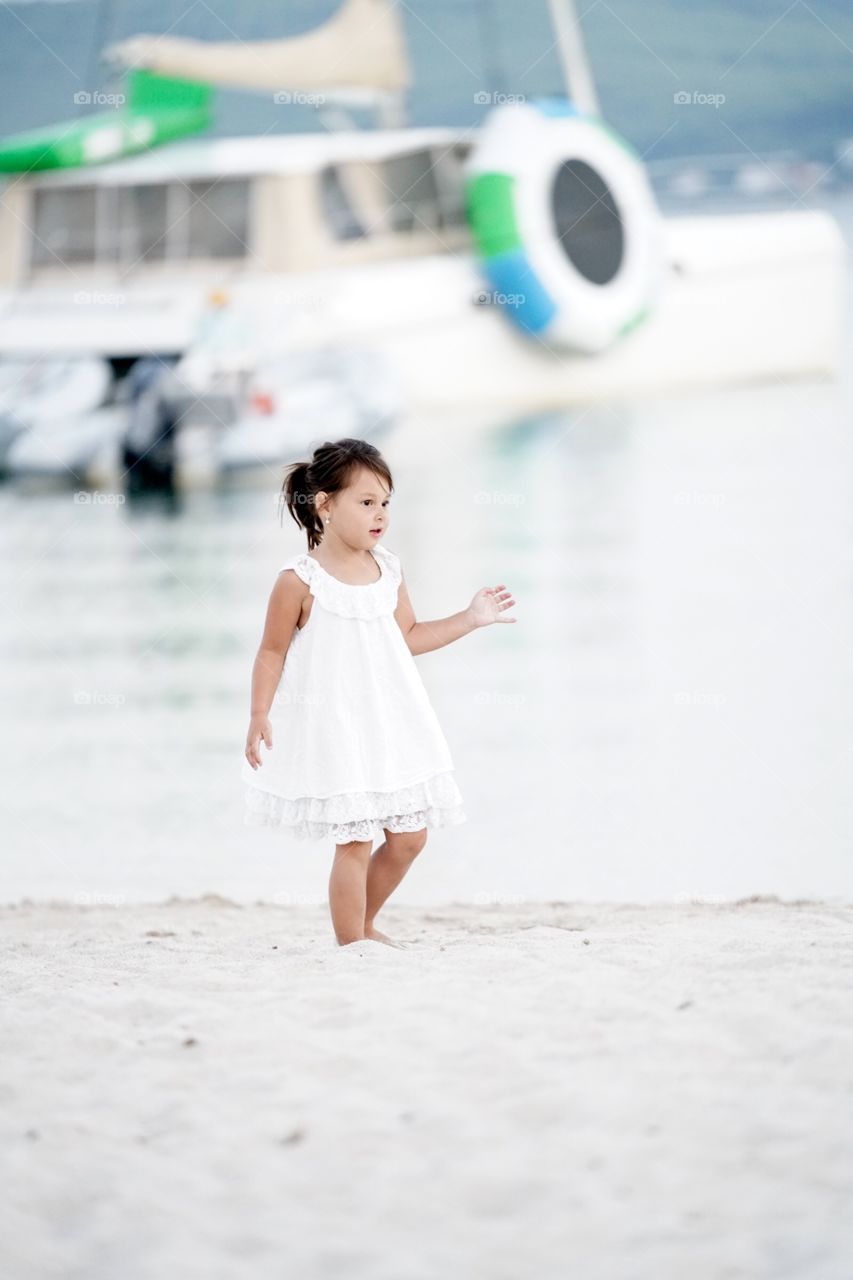 Girl in white dress walking on sand at beach