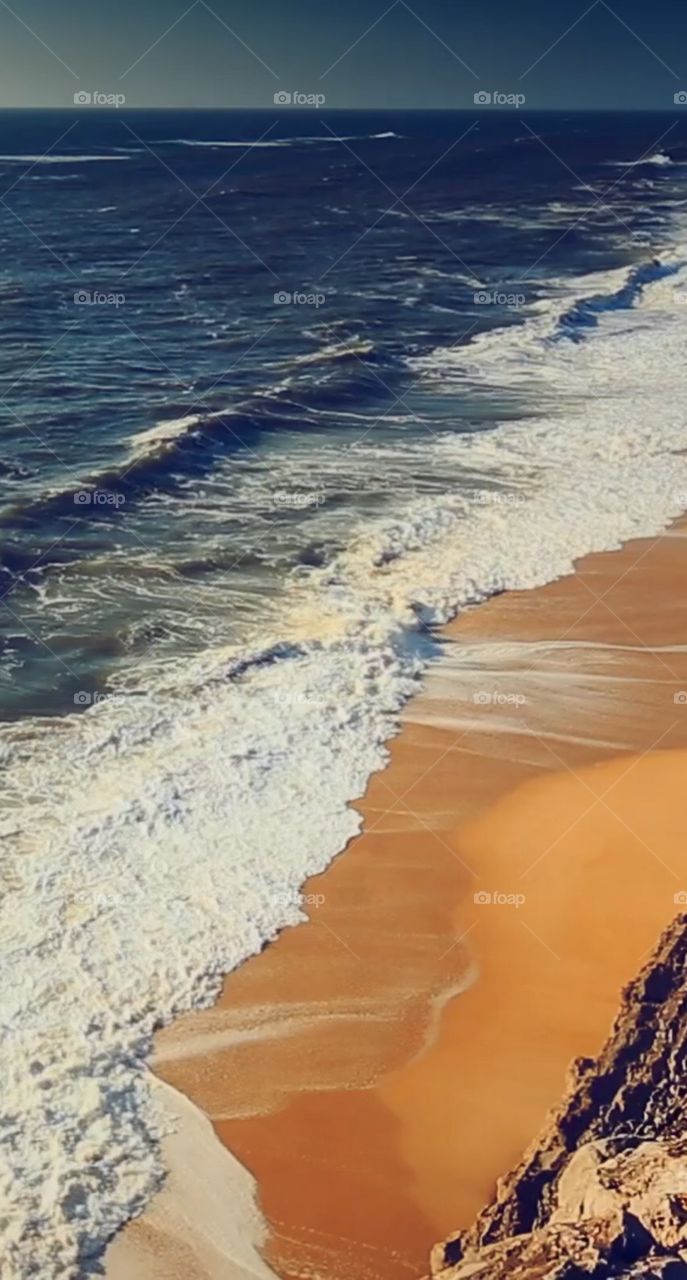 Beautiful golden sand being washed by dark blue water