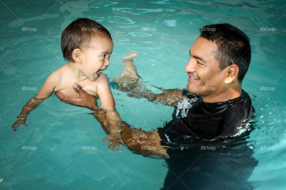 Father and baby daughter are having fun in a swimming pool