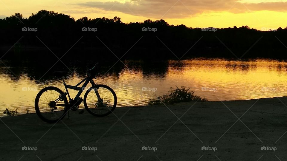 Bicycle silhouette in the golden sunset at the lake