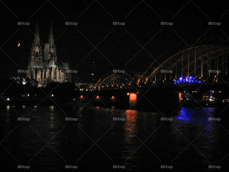 Night view of the Dom and Hohenzollern Bridge with cresent moon in Cologne, Germany.